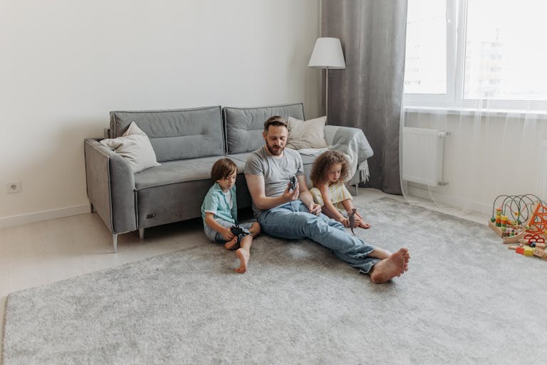 Father and two children enjoy playtime in the living room. Warm family bonding moment captured indoors.